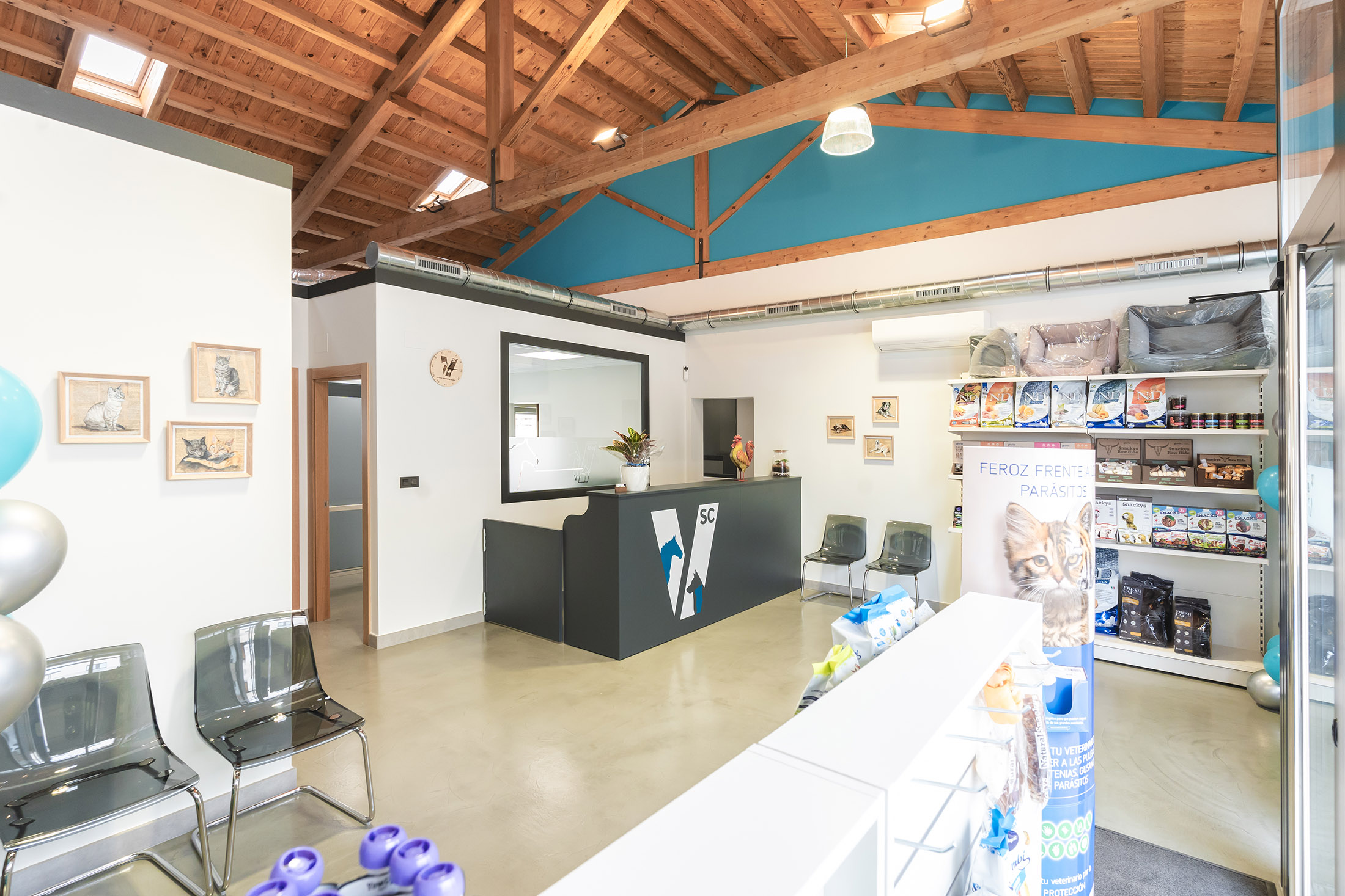 Interior de la clínica veterinaria mostrando la zona de recepción con techo de cerchas de madera expuestas